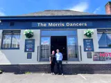 A woman and a man standing together, smiling, outside the Morris Dancers pub in Bolton