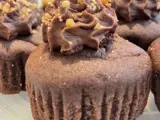 chocolate cupcake with a swirl of chocolate icing and nuts sprinkled on top