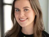 A headshot of a young brown haired woman smiling at the camera