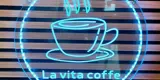 A circular neon light with a neon coffee cup in the middle and a neon circle around the edge. At the bottom of the light it says "La Vita Coffe"
