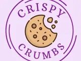 a lilac background with a graphic of a bitten cookie with crumbs in the centre. "Crispy Crumbs" is written around the cookie in purple with Crispy being at the top and Crumbs being at the bottom